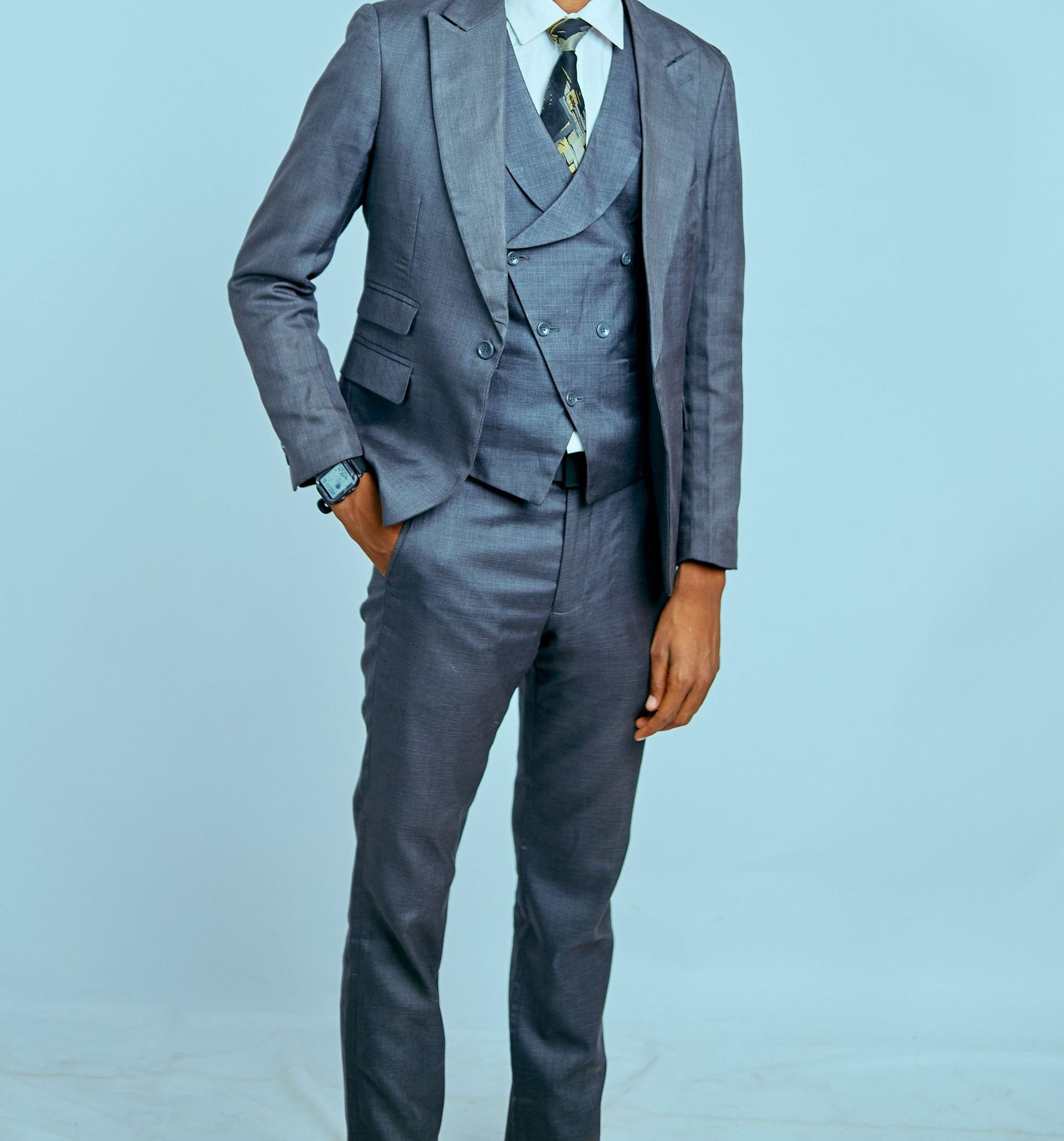 Confident man wearing a gray suit and sunglasses in a studio setting, looking elegant and professional.