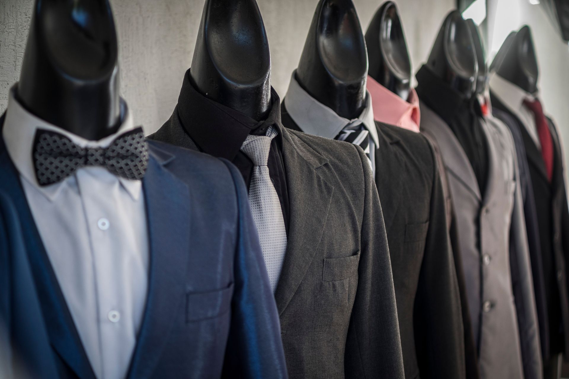 Close-up of mannequins adorned in elegant men's suits in a store setting, showcasing diverse styles.